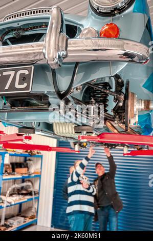 Überprüfen der Unterseite. Austin Healey 3000 auf einer Auffahrrampe bei Rawles Motorsport in Hampshire, England Stockfoto
