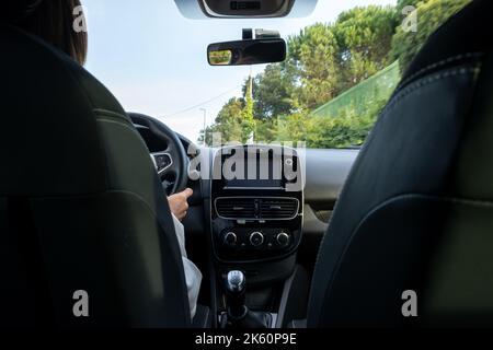 Fahrende Frau, Blick vom Rücksitz aus in einem niedrigen Winkel zum Armaturenbrett des Fahrzeugs. Aus dem POV des hinteren Beifahrersitzes. Stockfoto