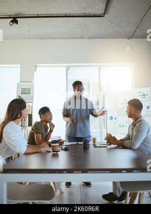 Eine Gruppe von glücklichen und vielfältigen Geschäftsleuten, die sich bei der Arbeit in einem Büro treffen. Junger afroamerikanischer Geschäftsmann im Gespräch während einer Präsentation bei Stockfoto