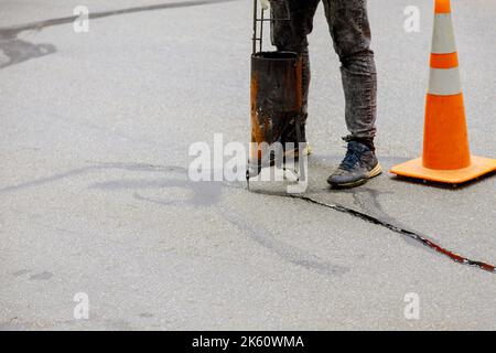 Dichtfugenriß in Asphaltoberflächen-Restaurierungsarbeiten Asphaltische Fugenabdichtung Stockfoto