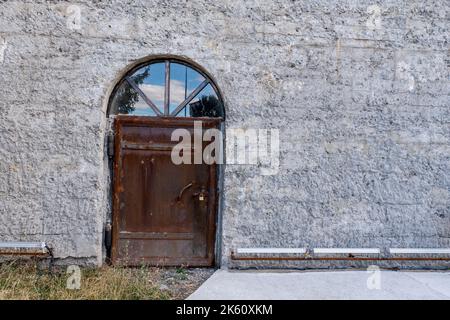 Der Eingang eines alten Industriegebäudes oder Depots mit einer alten, rostigen Metalltür. Hochwertige Fotos Stockfoto