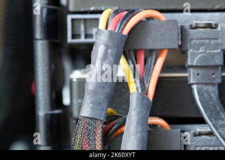 Stark verschmutzte Kabel mit Anschlüssen sind an die Festplatte des Computers angeschlossen. HDD- und SSD-Disk. Alte farbige Drähte in umflochtener Umwicklung. Elektrische Litze Stockfoto