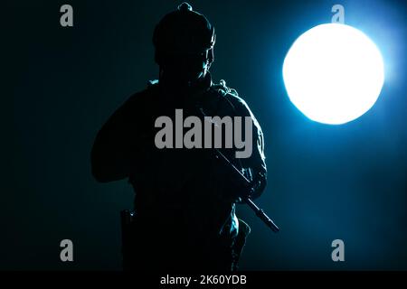 Armeesoldat in Schutzkampfuniform mit Special Operations Forces Combat Assault Rifle, das nachts im Mondlicht eingesetzt wird Stockfoto