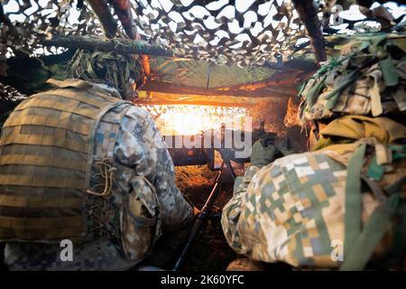 Nahaufnahme Soldaten feuern eine 50 Cal Machine Kanone mit verbranntem Messing um sie herum Stockfoto