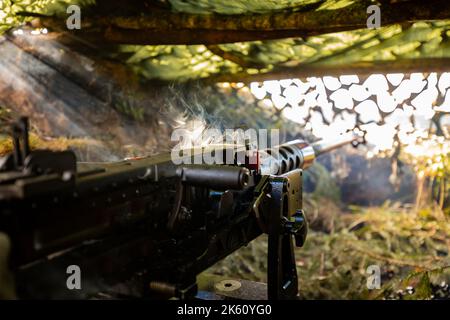 Nahaufnahme Soldaten feuern eine 50 Cal Machine Kanone mit verbranntem Messing um sie herum Stockfoto