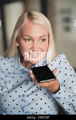 Fröhliche Dame, die drinnen ein Telefongespräch führt Stockfoto