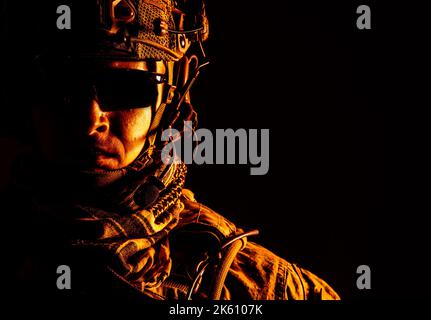 Elite-Mitglied der US Army Ranger in Kampfhelm und dunkler Brille. Studioaufnahme, dunkelschwarzer Hintergrund, Blick auf die Kamera, dunkler Kontrast, getönt und farbig Stockfoto