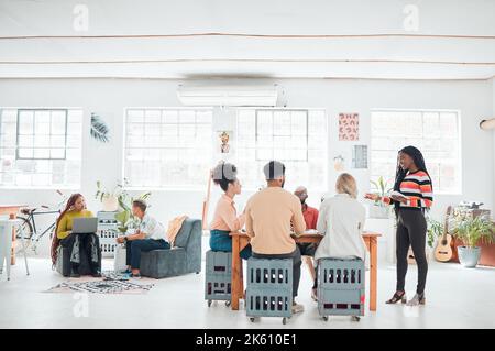 Eine Gruppe von verschiedenen Geschäftsleuten, die sich in einem modernen Büro auf der Arbeit treffen. Junge glückliche afroamerikanische Geschäftsfrau, die eine Präsentation eines Stockfoto