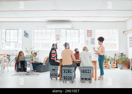 Eine Gruppe von verschiedenen Geschäftsleuten, die sich in einem modernen Büro auf der Arbeit treffen. Junge glückliche gemischte Rasse Geschäftsfrau tun eine Präsentation einer Idee Stockfoto