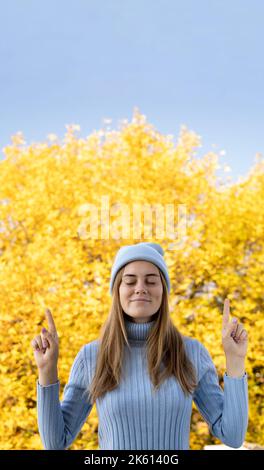 Die junge kaukasische Frau im Herbst verlässt den Hintergrund und gibt einen Daumen nach oben. Vertikales Banner. Stockfoto