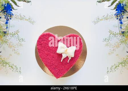 Rote herzförmige Torte mit Blumen. Torte mit Creme zum Valentinstag. Draufsicht Stockfoto