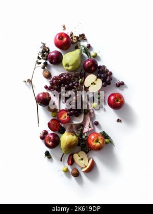 Komposition mit frischen Sommerfrüchten und Beeren auf weißem Hintergrund. Trauben, Pflaumen und Äpfel im Sonnenlicht. Stockfoto