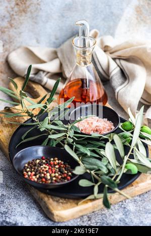 Gewürze in den Schüsseln und Olivenöl auf dem Betontisch Stockfoto