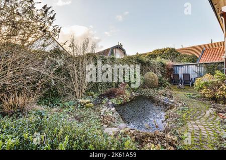 Backsteinhaus mit gepflegter gepflasterter Terrasse mit kleinem Garten und Teich und Stockfoto