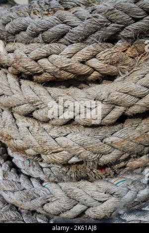 Dickes, verwittertes Seil, mit Schmutz bedeckt und tagsüber im Hafen in Spule gerollt Stockfoto