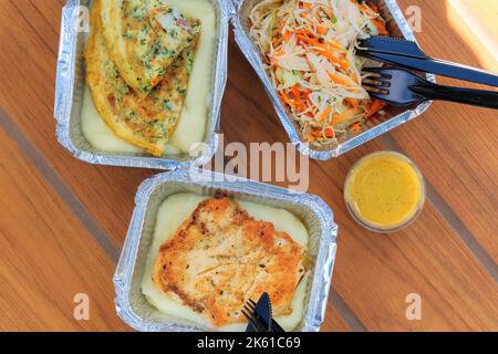 Essen zum Mitnehmen. Verschiedene Aluminium-Lunchbox mit Hühnerfilet, Kartoffeln und Salat. Lieferung von Lebensmitteln. Draufsicht. Stockfoto