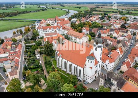 Torgau, Deutschland. 06. Oktober 2022. Torgaus Innenstadt mit Schloss Hartenfels (l) und Marienkirche. Vom 23. April bis 9. Oktober war Torgau Gastgeber der Sächsischen Landesgartenschau 9.. Der nächste Veranstalter war Aue-Bad Schlema unter dem Motto 'von der Wismutschacht zur Pracht der Blumen'. (Luftaufnahme mit Drohne) Quelle: Jan Woitas/dpa/Alamy Live News Stockfoto