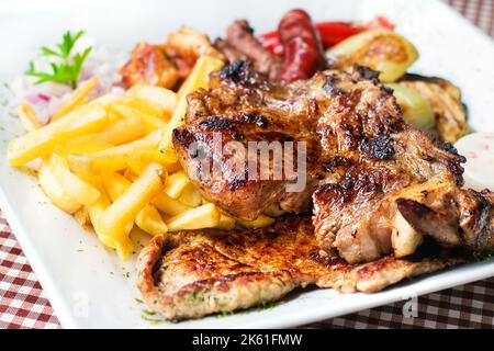 Traditionelle Balkan gemischte Grillplatte - verschiedene Arten von bbq Fleisch und Gemüse mit Pommes frites, selektive Fokus Stockfoto