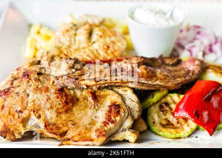 Traditionelle Balkan gemischte Grillplatte - verschiedene Arten von bbq Fleisch und Gemüse mit Pommes frites, selektive Fokus Stockfoto