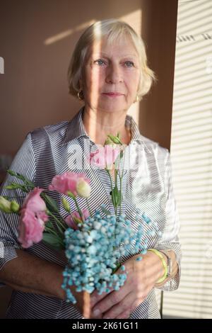 Gealterte Frau mit Blumenstrauß. Stockfoto
