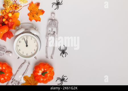 Wecker mit abgefallenen Blättern Kürbisse Skelette Spinnen. Übergangswechsel der Herbstzeit, Wechsel der Jahreszeiten halloween Stockfoto