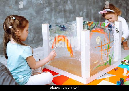 Kinder malen Regenbogen. Gruppe von Kindern Mädchen mit Lehrer lernen Farbe in der Klassenschule. Schüler zeichnen Regenbogen. Stockfoto