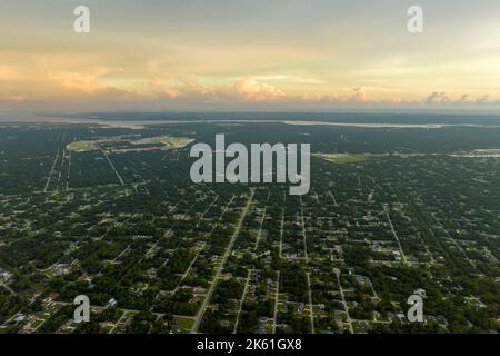 Luftlandschaftsansicht von privaten Vorstadthäusern zwischen grünen Palmen in Florida ruhige ländliche Gegend bei Sonnenuntergang Stockfoto