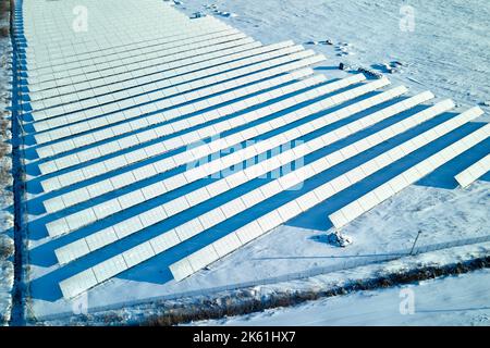 Luftaufnahme eines schneebedeckten nachhaltigen Elektrizitätswerks mit Reihen von Photovoltaik-Solarzellen zur Erzeugung sauberer elektrischer Energie. Niedrig Stockfoto