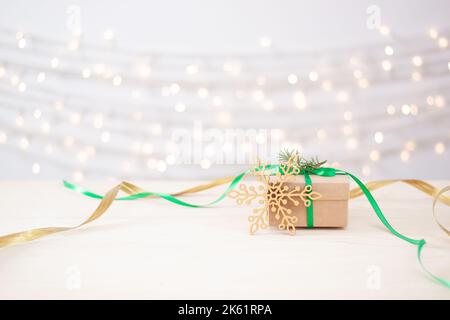 Umweltfreundliches Verpackungsgeschenk in Bastelpapier auf Holztisch. Null-Verschwendung Weihnachtsfeiertage Konzept. Nahaufnahme, Kopierbereich. Stockfoto