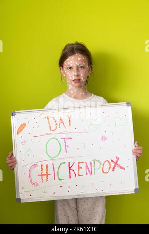 Ein kleines Schulmädchen mit Windpocken zeichnet eine Botschaft auf das Whiteboard im Kinderzimmer, und antiseptische Creme wird auf Gesicht und Körper aufgetragen Stockfoto