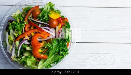 Blick von oben auf frischen Gemüsesalat in Glasschüssel über Holztisch, Kopierbereich Stockfoto