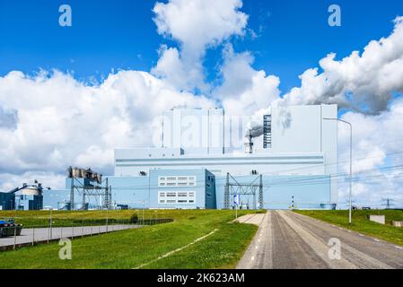 Blick auf ein Kohlekraftwerk an einem sonnigen Sommertag. Dichte, weiße Rauchschornsteine bilden einen Kamin. Stockfoto