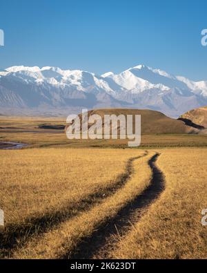 Morgens Landschaftsansicht der schneebedeckten Trans Alay Bergkette mit Lenin Peak und Spuren im Vordergrund im Süden Kirgisistans Stockfoto