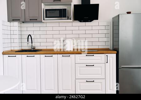 Weiße Schränke mit Holztheke der modernen Küche Stockfoto