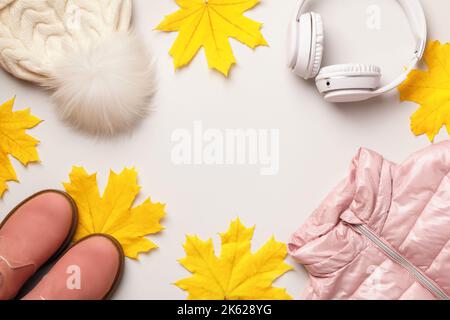 Ein Satz warmer Herbst-Winter-Kleidung und Accessoires für ein Mädchen auf grauem Hintergrund. Jacke Hut Schuhe Kopfhörer. Stockfoto