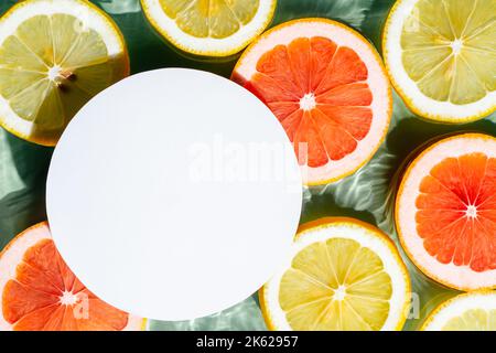 Weißer Kreis kopieren Raum in transparentem frischen berauschenden Wellenwasser mit Flecken Hintergrund, Zitrone, Grapefruit Zitrusscheiben. Sommerfrische, gesund Stockfoto