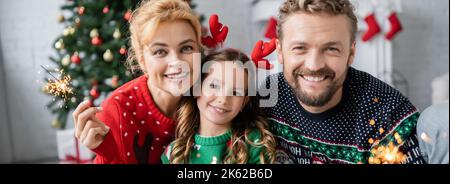 Glückliche Familie mit Kind halten Wunderkerzen während der weihnachtsfeier zu Hause, Banner, Stock Bild Stockfoto