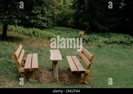 Ruhige Herbstsaison im Deutschen Park. Wunderschöne Landschaft mit Tisch und Bank im Herbstwald. Picknickbank und Tisch im Autumn Park. Ahornbäume Und Stockfoto