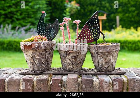 Zwalm, Region Ostflandern - Belgien - 07 14 2021 Nahaufnahme von dekorativen Pflanzen und Gartenspielzeug in einem Steintopf Stockfoto