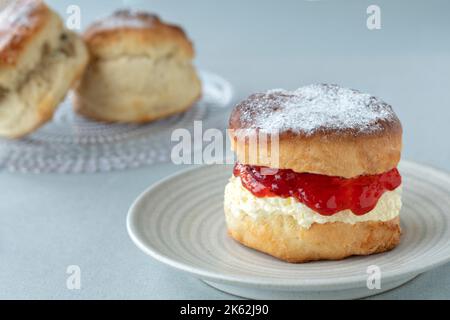 Ein frischer traditioneller englischer hausgemachtes Scone. Der Kuchen wird gespalten und mit Marmelade gefüllt und mit dickem gerinntem Rahm gekrönt. Ein köstlicher Devon-Cream-Tee. Stockfoto