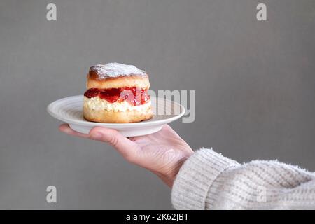 Ein frischer traditioneller englischer hausgemachtes Scone. Der Kuchen wird gespalten und mit Marmelade gefüllt und mit dickem gerinntem Rahm gekrönt. Ein köstlicher Devon-Cream-Tee. Stockfoto