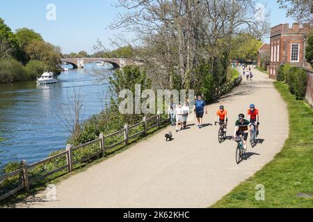 Menschen, die den sonnigen Frühlingstag auf dem Thames Path in Hampton, Richmond upon Thames, London, England, Großbritannien genießen Stockfoto