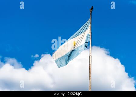 Argentinische Flagge, die auf einem Fahnenmast gegen einen bewölkten Himmel fliegt. Patriotisches Emblem von Argentinien Stockfoto