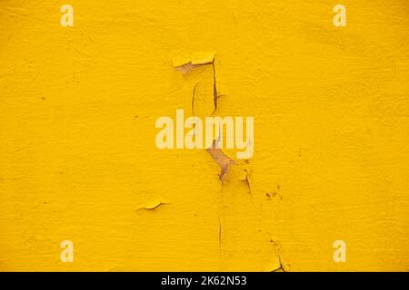 Fassade einer Hauswand mit gelber geschälter Farbe als Hintergrund, einer Wand mit gelber Farbe Stockfoto