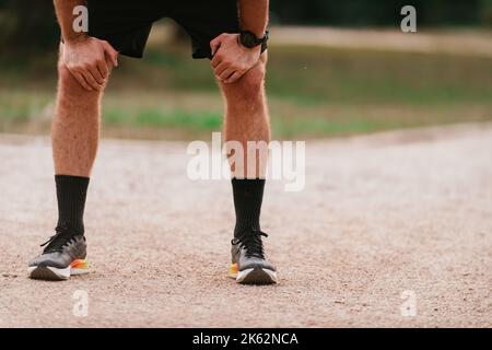 Nahaufnahme der Hände eines männlichen Athleten auf den Knien, die nach einem anstrengenden morgendlichen Lauf ruhen Stockfoto