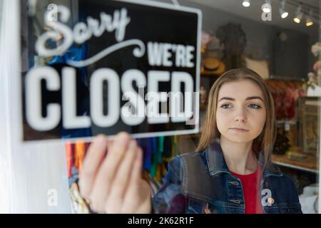 Traurige Weibliche Inhaberin Von Kleinunternehmen, Die Runde Dreht, Geschlossenes Schild Im Schaufenster Stockfoto