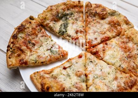 Pizza in Scheiben mit blauem Käse auf einem weißen Teller. Stücke frisch gekochte Pizza. Stockfoto