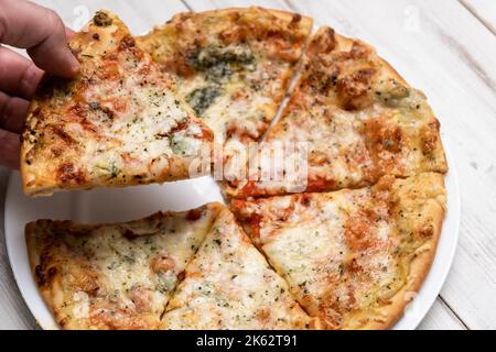 Pizza in Scheiben mit blauem Käse auf einem weißen Teller. Stücke frisch gekochte Pizza. Stockfoto