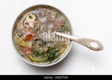 Gemüsesuppe mit Fleischbällchen auf einem Teller auf weißem Hintergrund. Stockfoto