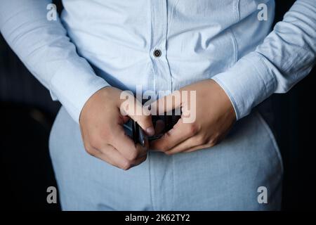 Eleganter Geschäftsmann Mann, der einen Gürtel an seiner Hose befestigt er Trägt ein weißes Hemd Stockfoto